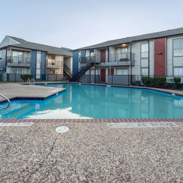 An inviting swimming pool area surrounded by apartment buildings under clear blue skies.
