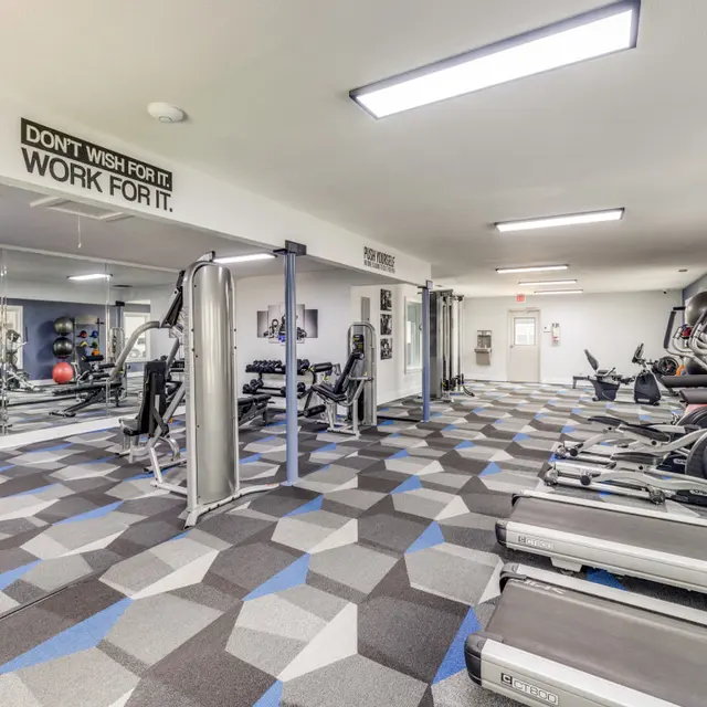 Interior view of a gym featuring various exercise machines, equipment, and motivational wall art.