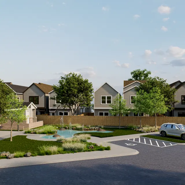 A scenic view of a residential complex featuring modern homes, a landscaped area with trees, and a small pond.
