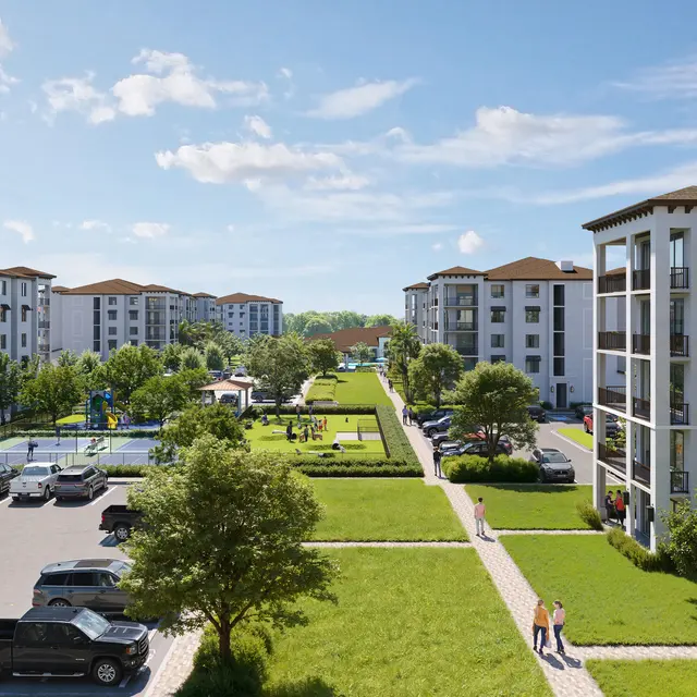 A modern apartment complex with multiple white buildings, green lawns, and a playground area. Cars are parked in the vicinity, and people are walking along the pathways.