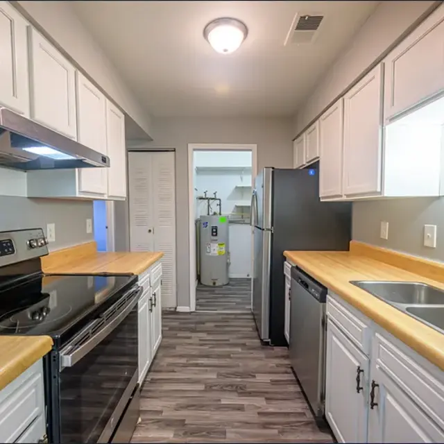 Modern Kitchen Design A modern kitchen with wooden countertops, stainless steel appliances, and light gray cabinets, featuring an open layout and a view into another room.