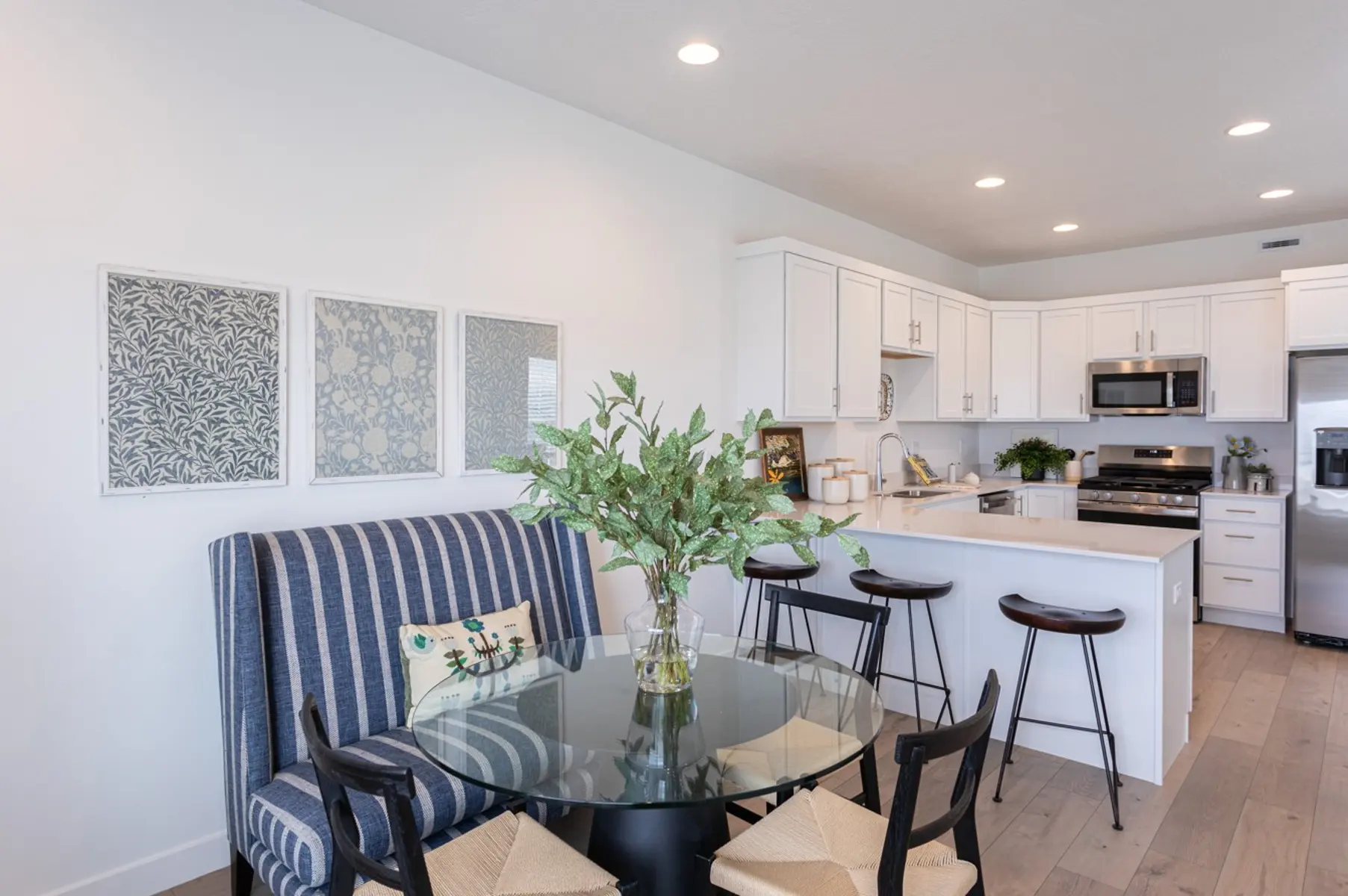 Modern Kitchen and Dining Area A modern kitchen and dining area featuring a round glass table with chairs, a spacious kitchen with white cabinets, and decorative wall art.