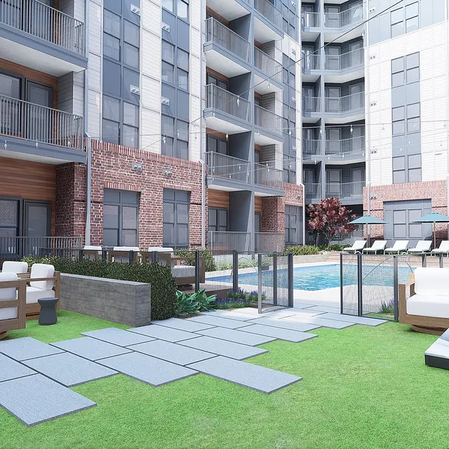 A modern outdoor pool area surrounded by apartment buildings, featuring lounge chairs, outdoor seating, and green landscaping.