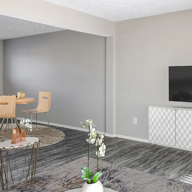 The Hideaway -  A modern living room featuring a grey couch, a round rug, a small coffee table with decorative items, a dining area with light wooden chairs and a table, and a television mounted on a white cabinet against a light grey wall.