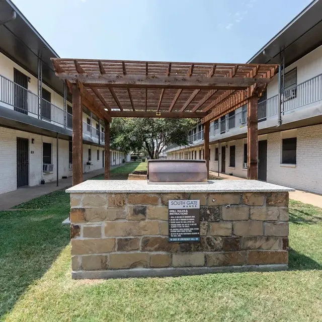 Courtyard Area of a Residential Complex A central courtyard in a multi-story building complex featuring a stone pedestal with a roof structure and surrounding grass areas.