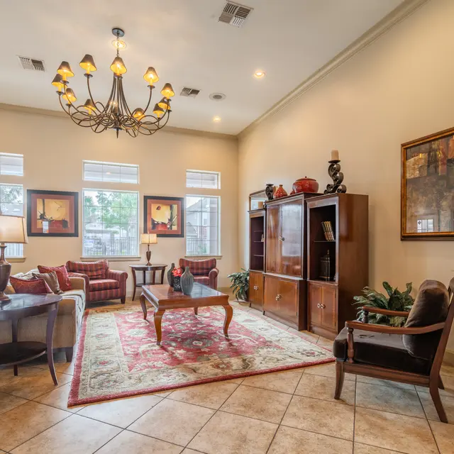 Elegant Living Room Interior A spacious living room featuring a chandelier, comfortable seating, and decorative wall art. The room has large windows allowing natural light to illuminate the space.