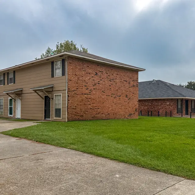 Exterior view of a two-story apartment building with a grassy area in front.