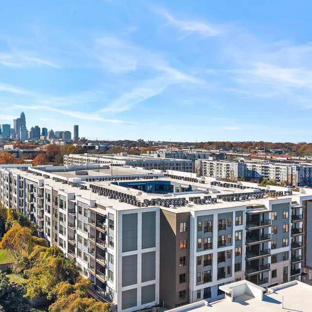 Aerial view of a modern apartment complex with a skyline in the background.