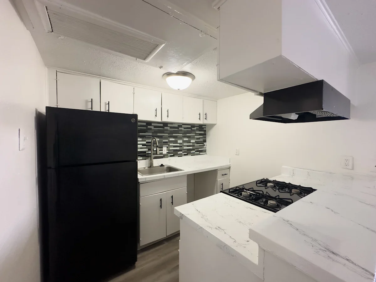 Modern Kitchen Design A modern kitchen featuring white cabinetry, a black refrigerator, a gas cooktop, and a stylish backsplash of patterned tiles.