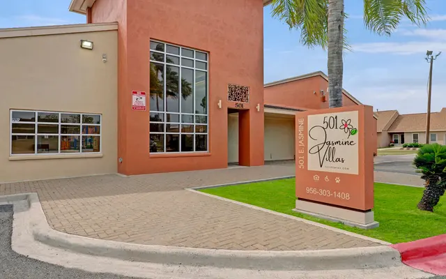 Exterior of Jasmine Villas Exterior view of a building with a modern design, featuring an entrance and a large sign that says '501 Jasmine Villas'.