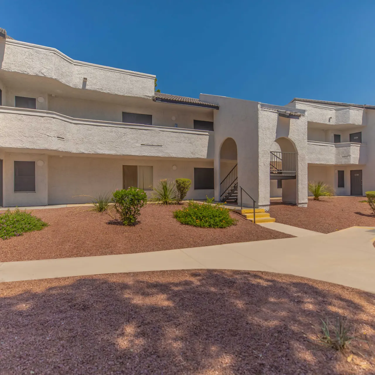 Exterior view of a contemporary apartment building with a smooth pathway and landscaped areas.