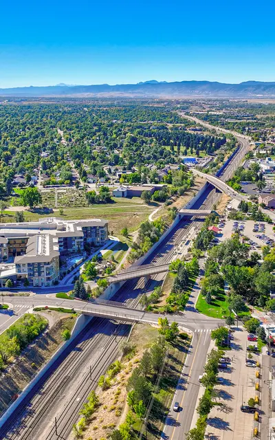 Aerial view of a city with green spaces, residential buildings, and highways running through it.