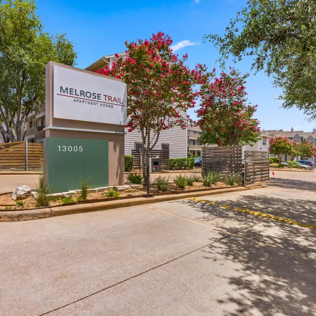 Entrance to Melrose Trail Apartment Homes with a sign and landscaping.