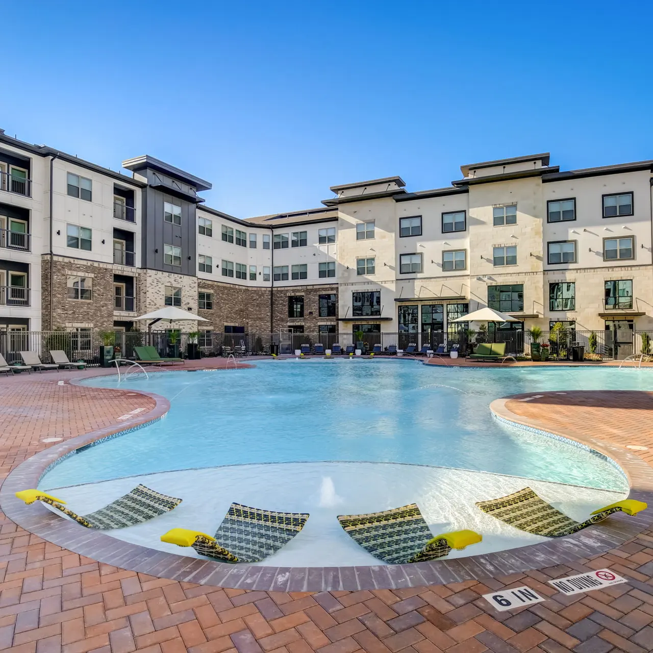 Modern Apartment Pool Area A spacious outdoor pool area surrounded by a modern apartment complex with multiple floors and patio seating