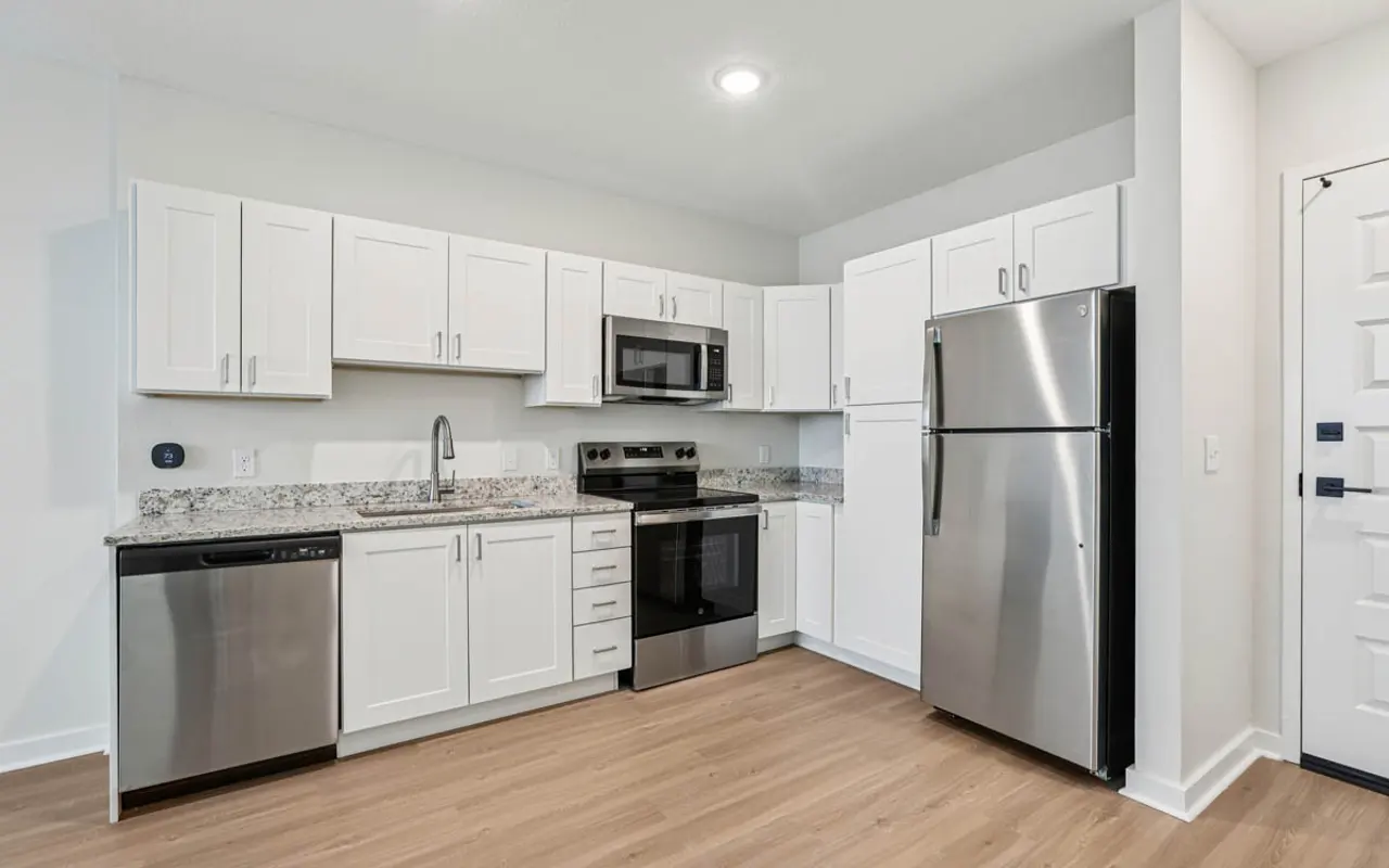 Stylish Modern Kitchen Modern kitchen with white cabinets, granite countertops, stainless steel appliances, and a wooden floor.