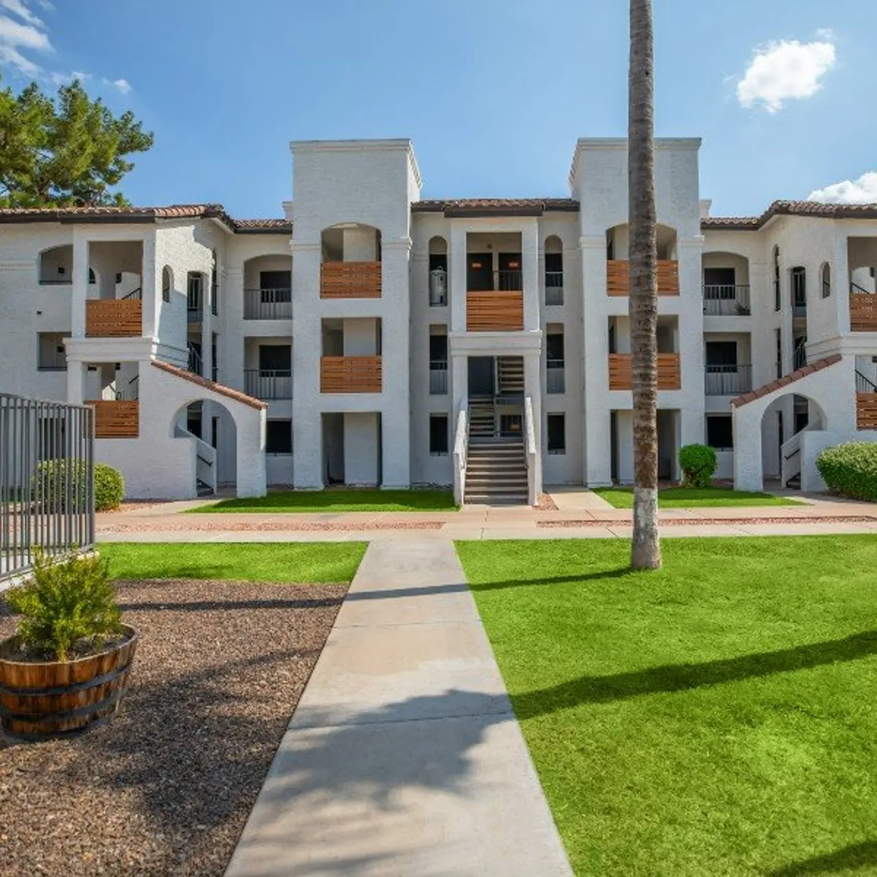 Exterior view of a modern apartment complex surrounded by greenery and palm trees