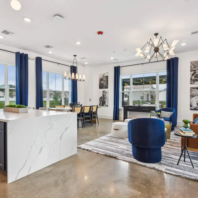 Contemporary Living Area with Kitchen Island A modern living area featuring a kitchen island with marble top, dark cabinetry, and a cozy seating arrangement with blue and leather chairs. Large windows with blue curtains provide natural light, and there are decorative pieces on the walls.