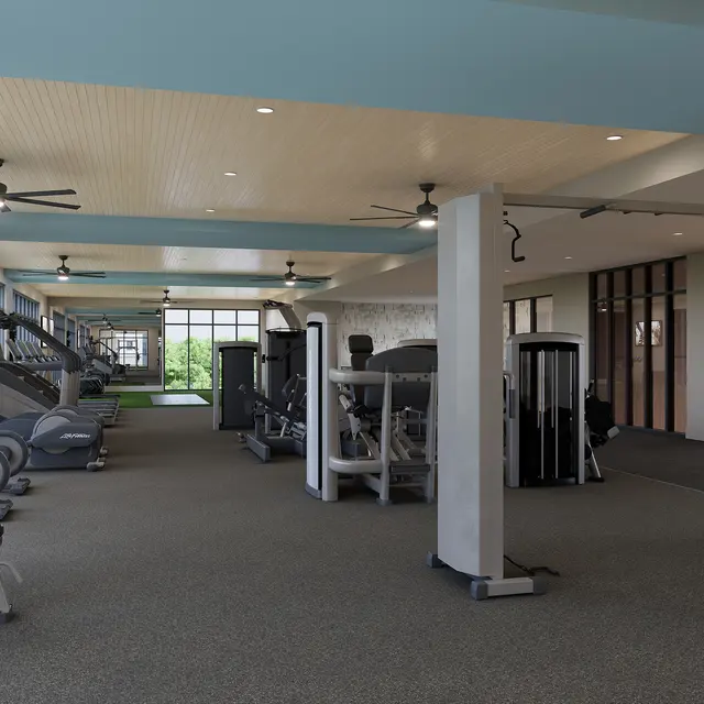 A spacious and modern gym with large windows, equipped with various exercise machines and free weights.