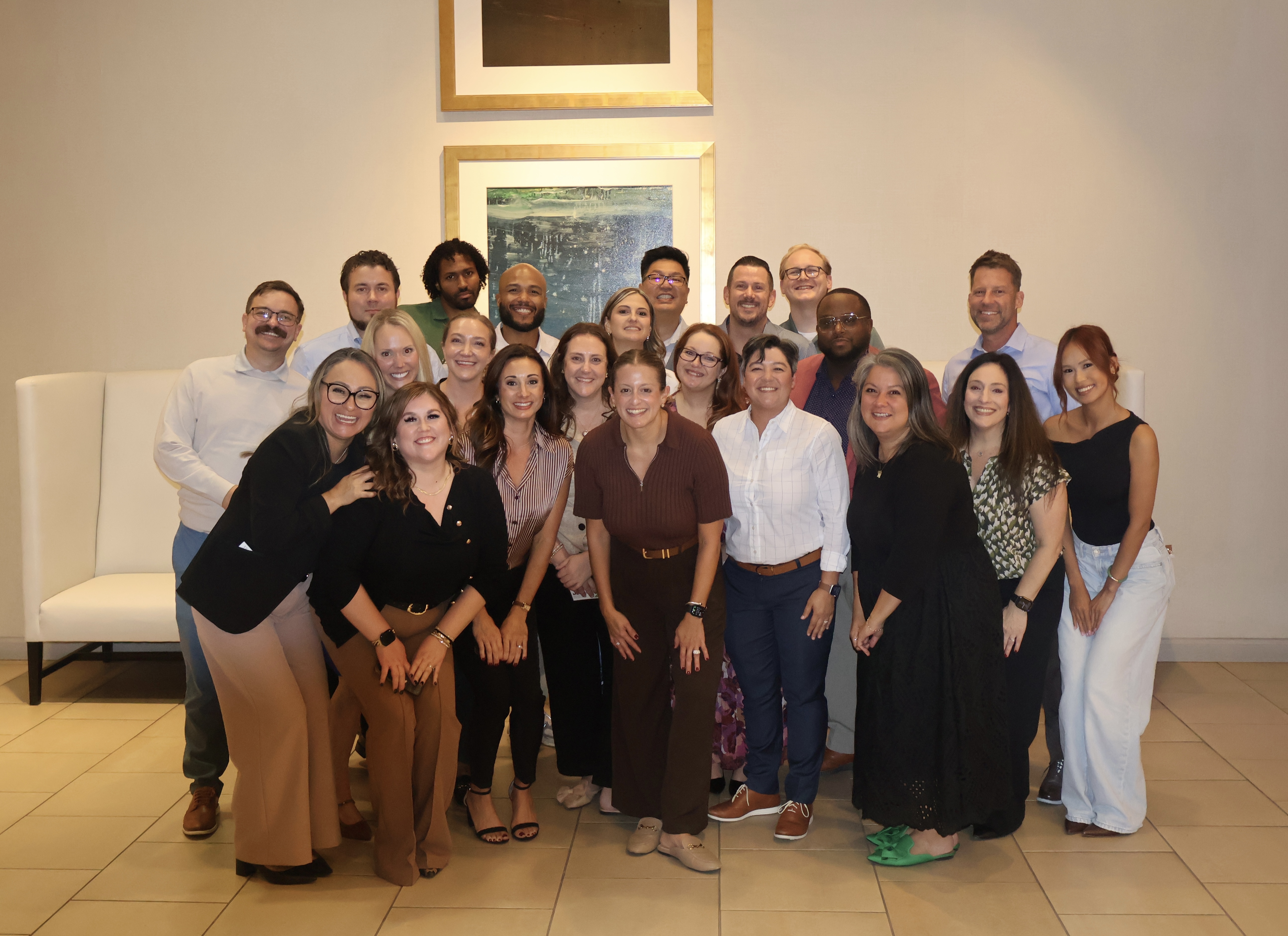 A large group of diverse people posing together in a well-lit indoor space, smiling for a group photo.