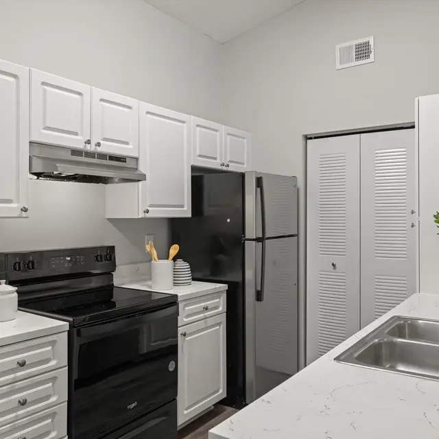 Modern kitchen with white cabinets and black appliances.