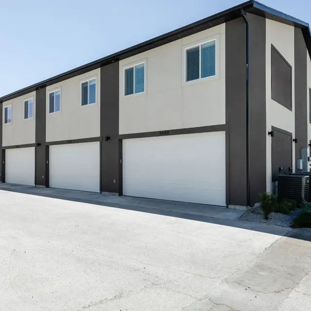 A modern apartment complex featuring a row of garage doors with multiple windows above.