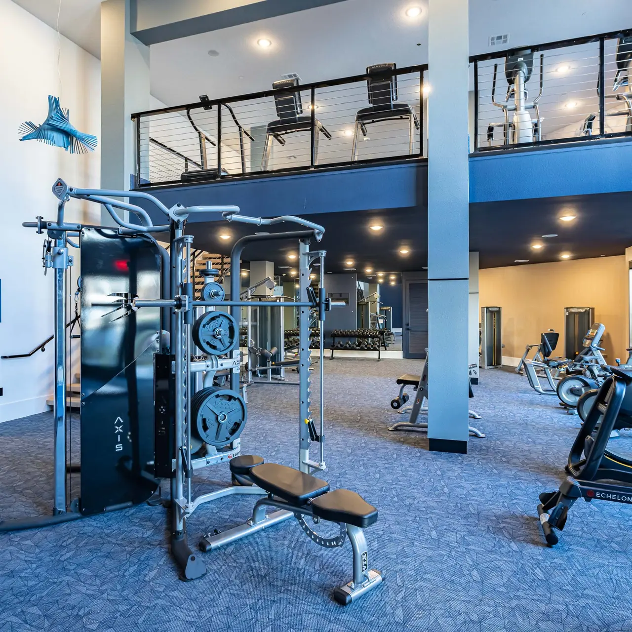 Interior of a modern gym featuring various exercise equipment including weight machines and cardio machines, with a spacious and well-lit layout.