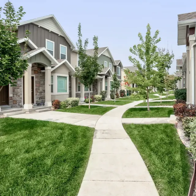A well-maintained pathway winding through a modern residential neighborhood with grass lawns and trees.