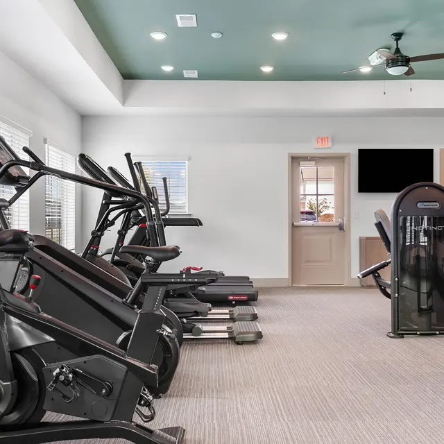 Interior of a modern gym with fitness equipment including treadmills and elliptical machines.