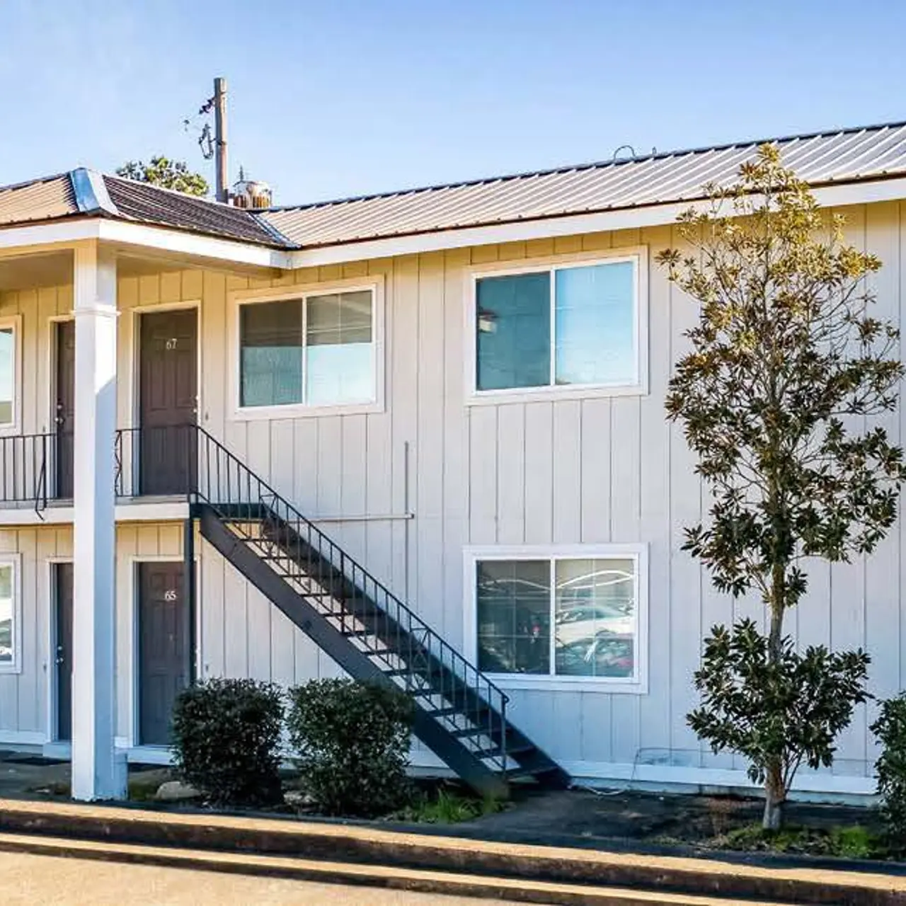 Haltere at Reserve - Exterior view of a two-story apartment building with a staircase and surrounding greenery.