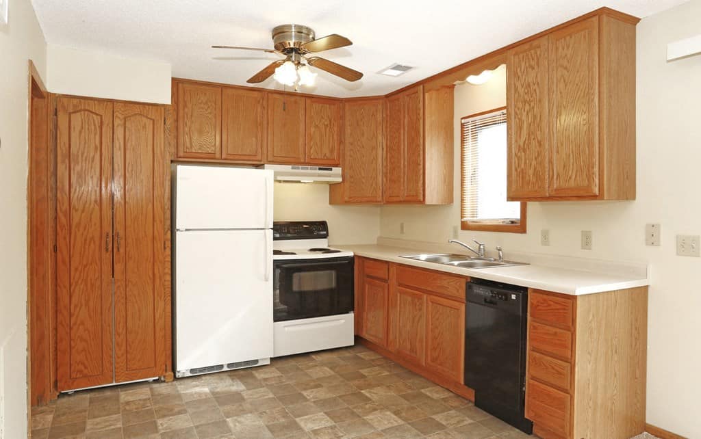 Inviting Kitchen Interior A kitchen with wooden cabinets, a ceiling fan, and various appliances including a refrigerator, oven, and dishwasher.
