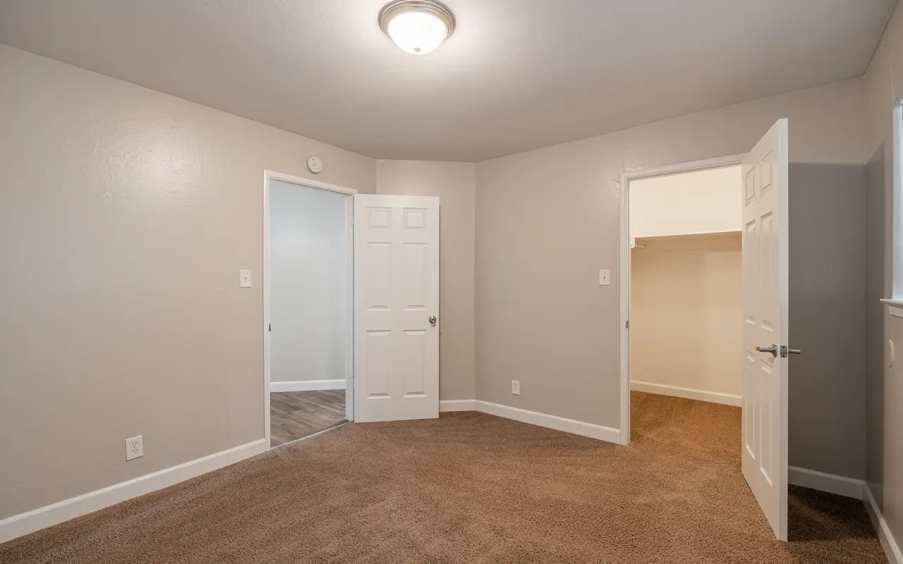 Empty room featuring beige carpet, gray walls, and two open doors leading to other areas.