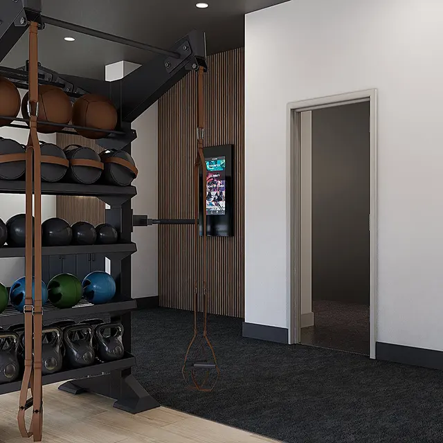 A modern gym interior featuring various exercise equipment including a punching bag, weight systems, and fitness balls, with wood and black tile accents.