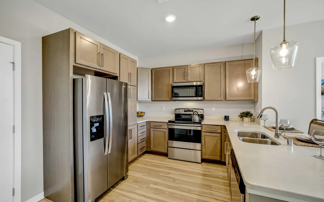 A modern kitchen featuring stainless steel appliances, wooden cabinets, and a light-colored countertop.