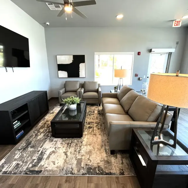 Contemporary Modern Living Room A modern living room featuring gray walls, comfortable beige sofas, a coffee table with a decorative plant, and a television mounted on the wall.