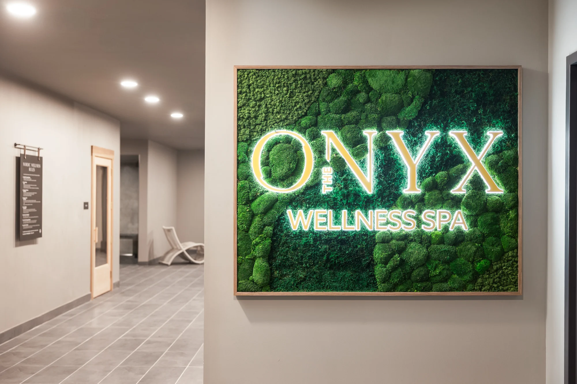 Sign for Onyx Wellness Spa, featuring green moss and illuminated letters