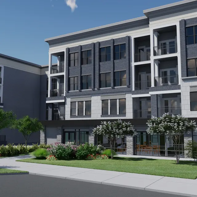 A modern multi-story apartment building with a mix of gray and white exterior, featuring balconies and large windows. The surrounding landscape includes shrubs and trees, with a well-maintained sidewalk.