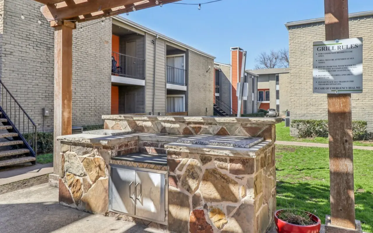 Outdoor grill area with stone structure next to an apartment complex.