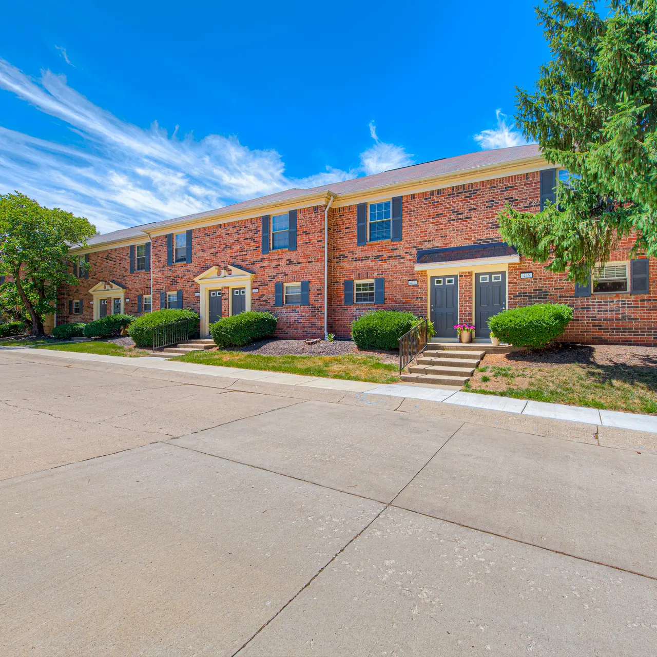 Apartment Complex Exterior Exterior view of a brick apartment complex with a concrete driveway and lush greenery.