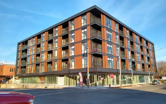 Contemporary Apartment Complex A contemporary four-story apartment building with a mix of wooden and glass facades, located on a corner street.