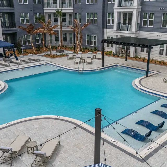 Modern Apartment Pool Area Swimming pool area of a modern apartment complex featuring lounge chairs, decorative trees, and a shaded gazebo.