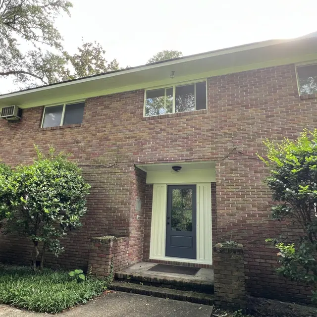Facade of a red brick house with green foliage