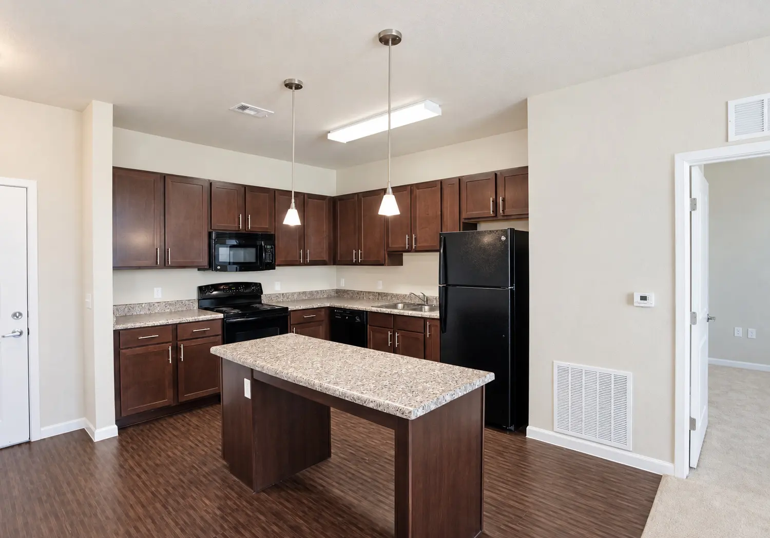 Modern Kitchen Design A modern kitchen featuring dark wooden cabinetry, a granite countertop island, and black appliances.