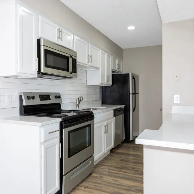 A modern kitchen featuring white cabinetry, stainless steel appliances, and a sleek countertop.