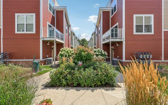 View of two red modern homes flanked by greenery and flowers.