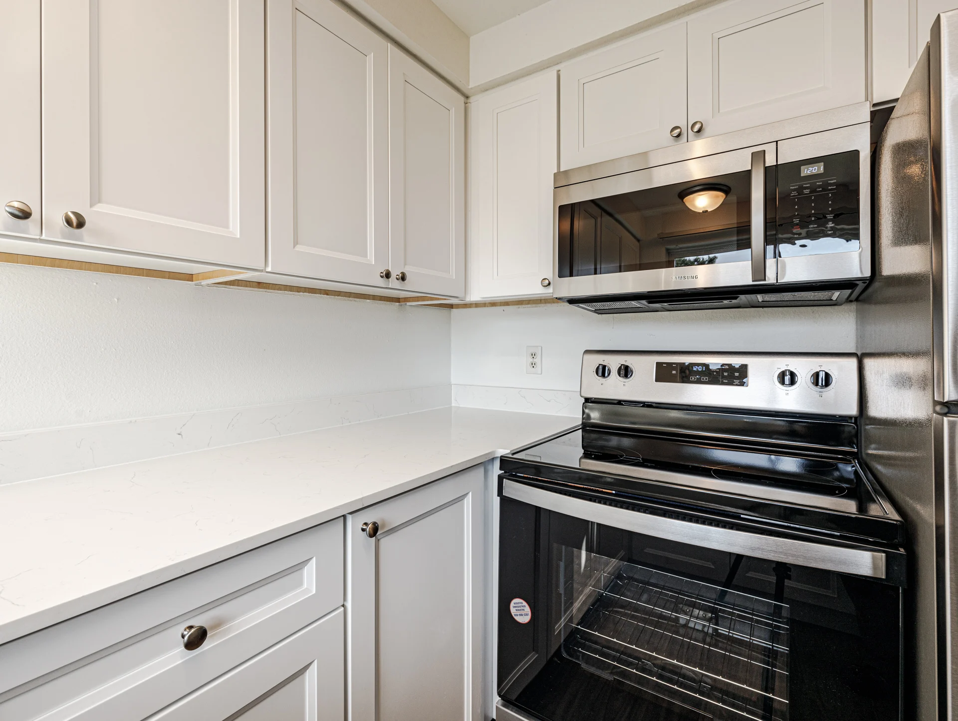 A modern kitchen featuring white cabinetry, stainless steel appliances, and a clean countertop.