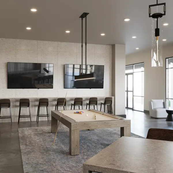 Contemporary Lounge Space A modern lounge space featuring two large screens mounted on a textured wall, a long table with barstools, and a pool table. Natural light enters through large windows, and there are stylish chairs in the corner.