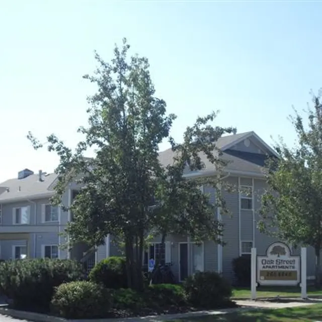 Oak Street Apartments Exterior view of Oak Street Apartments with trees and parked cars in foreground