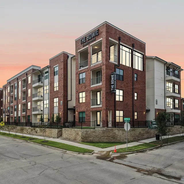 Exterior View of The Bowie Apartments Exterior view of a modern apartment complex named The Bowie, showcasing multiple stories with large windows at sunset.