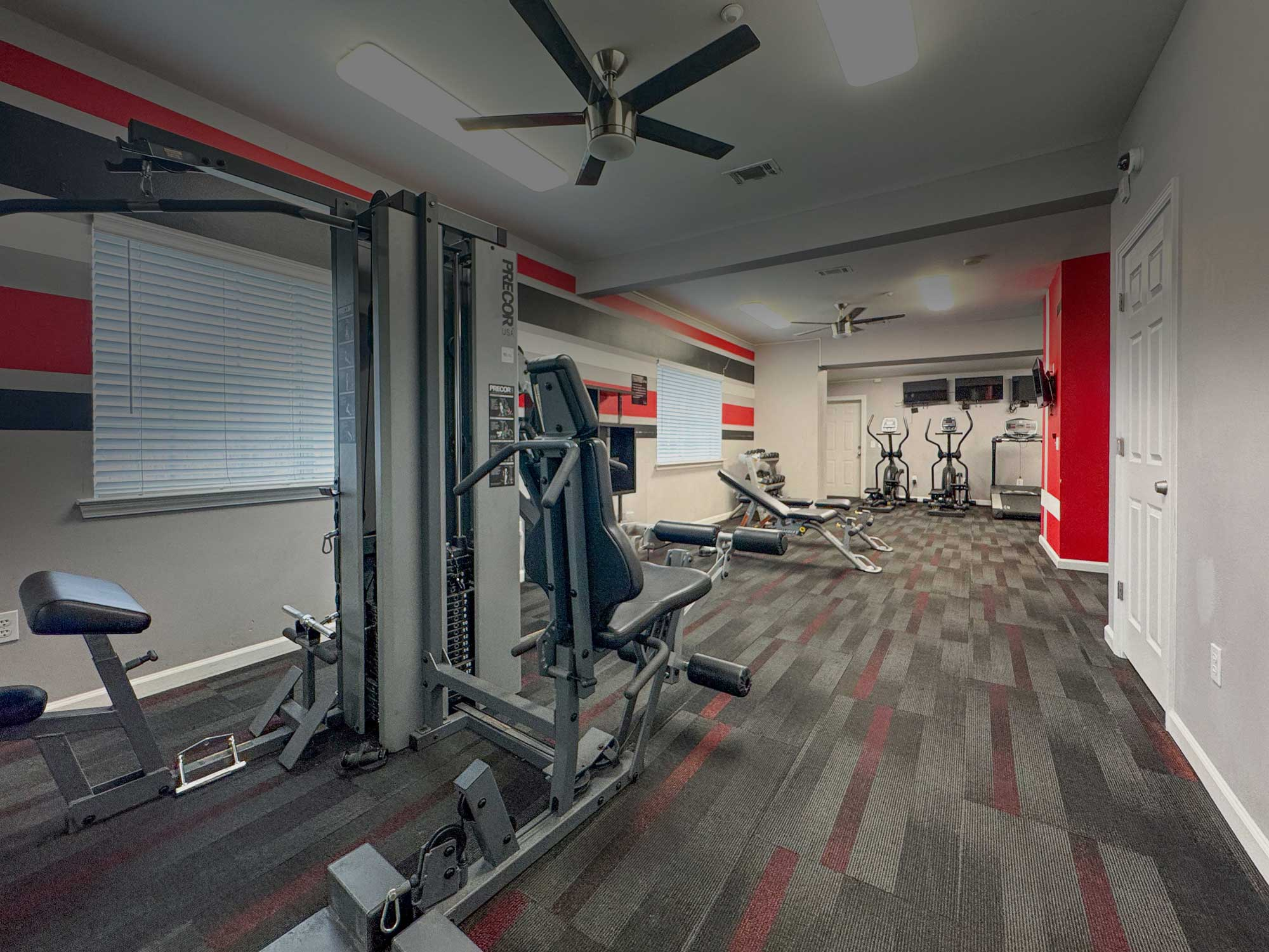 Interior view of a gym with workout machines and a carpeted floor
