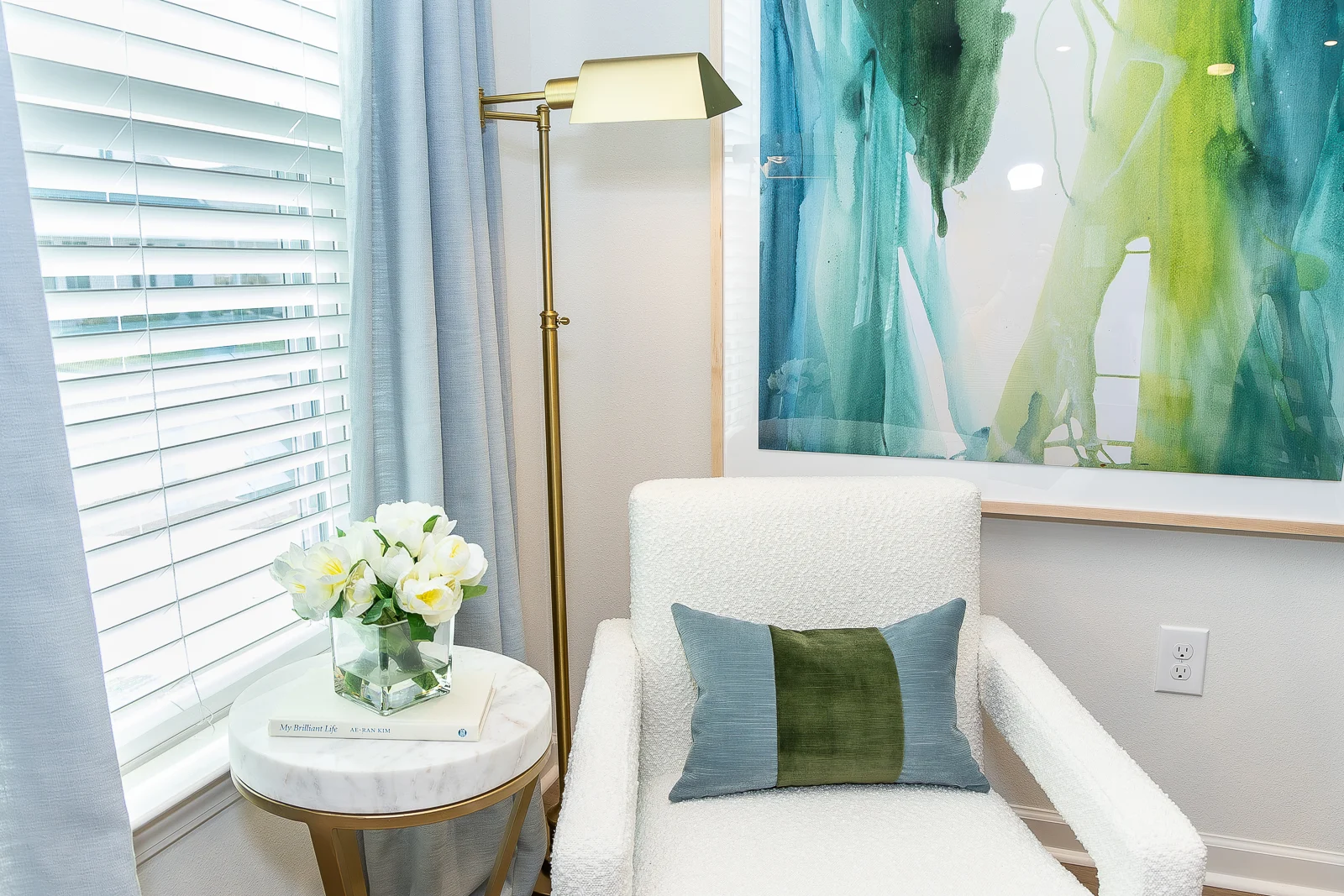 Stylish Reading Nook A cozy reading nook with a plush armchair, a decorative pillow, a small round table with flowers, and a colorful abstract painting on the wall.